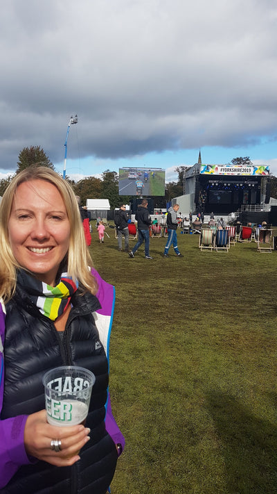 Woman wearing her world champion rainbow Ruffnek neck gaiter as a supporters scarf whilst watching the UCI cycle race on the big screen in Harrogate 2019