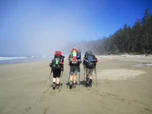 Hiking Adventure three hikers walking along a beach carrying rucksacks wearing a Ruffnek snood - West Coast Trail, Canada